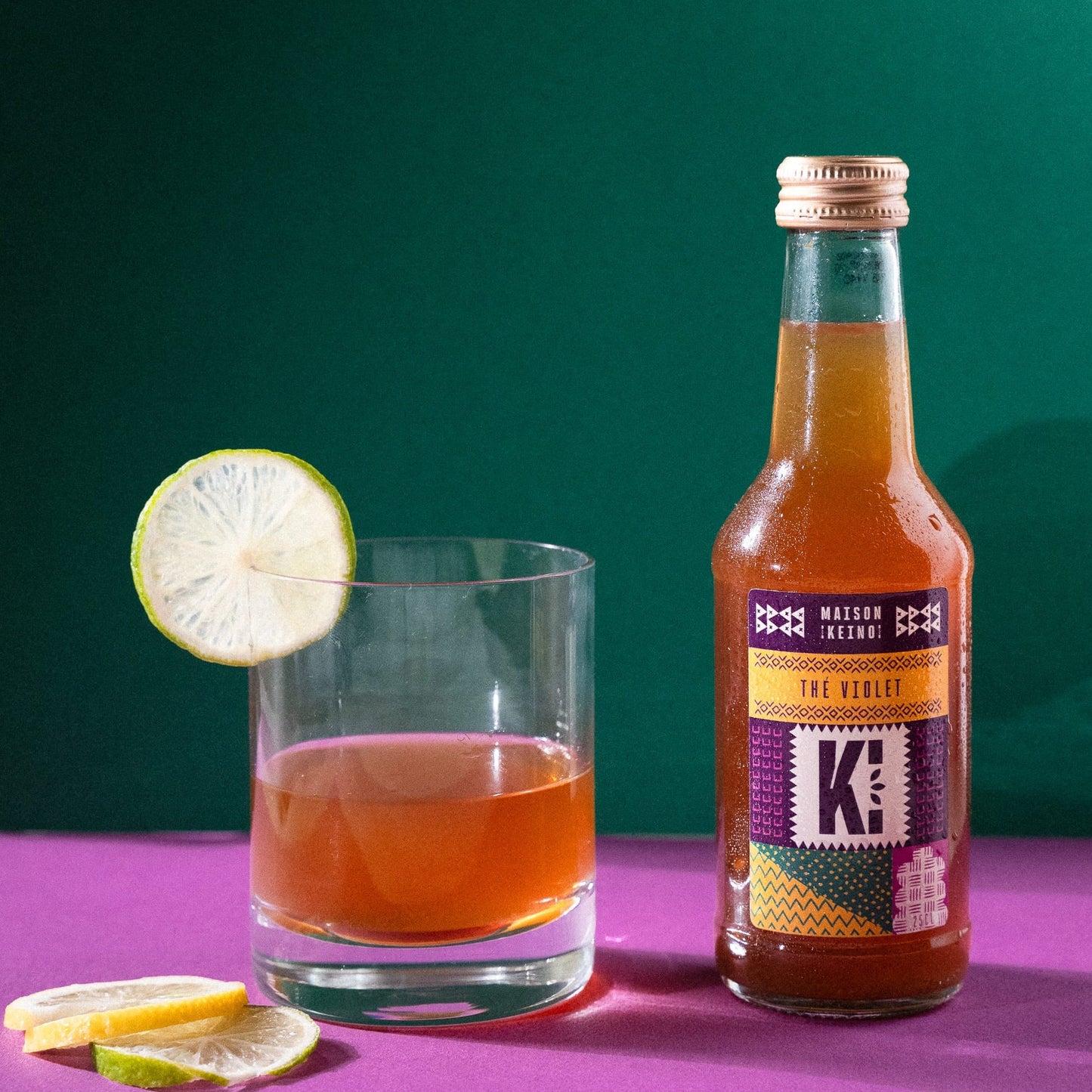 Thé glacé en bouteille violet Keino cultivé au Kenya dans le respect du commerce équitable, préparé à partir de thé bio récolté à la main par nos partenaires locaux. Cette boisson artisanale utilise le cultivar TRFK 306/1 aux feuilles naturellement pourpres du terroir kényan. Ce thé glacé audacieux révèle une amertume délicate adoucie par l'acidité vivifiante du citron, avec des arômes floraux subtils, riche en anthocyanines protectrices pour une hydratation rafraîchissante.